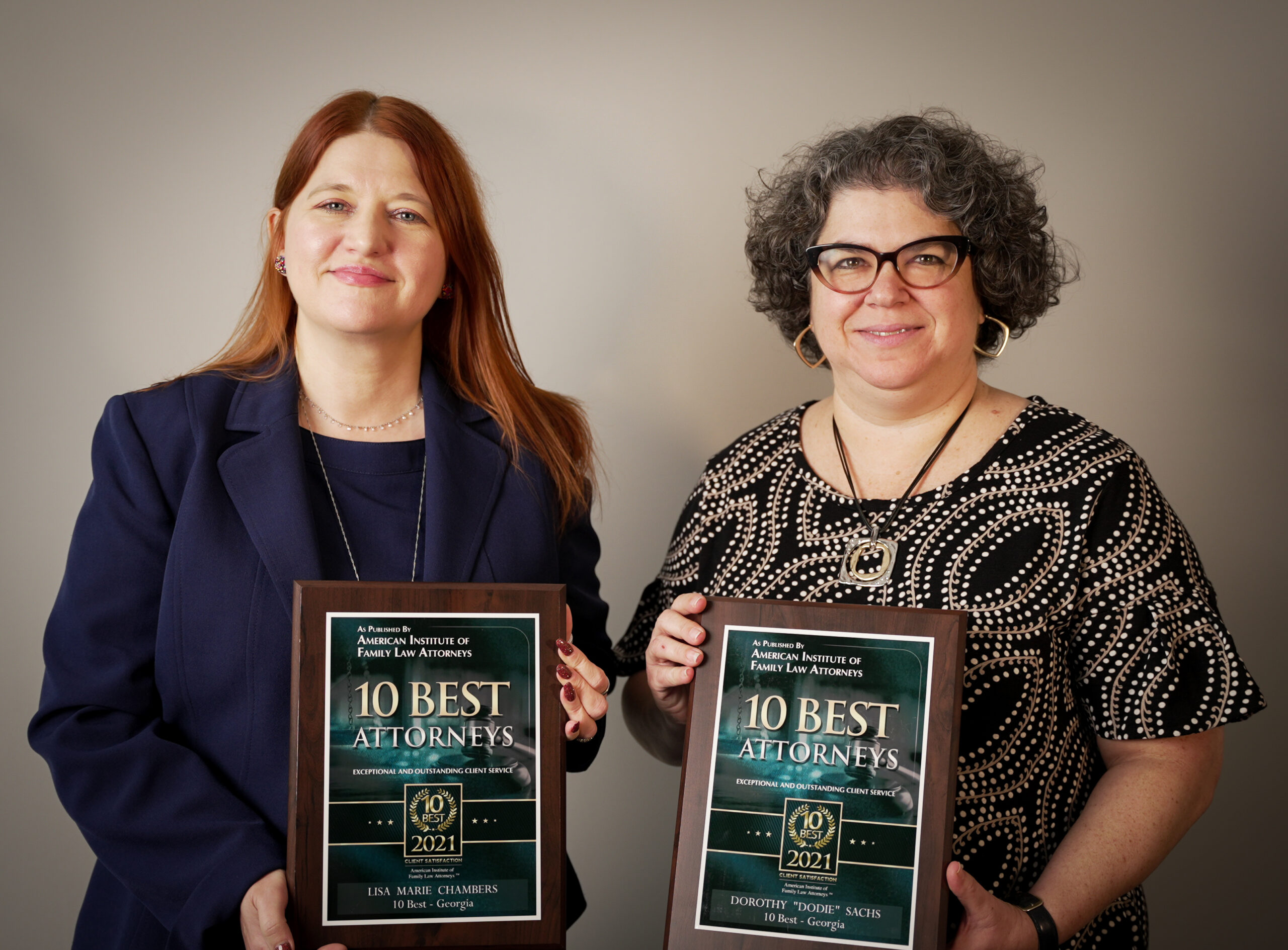 Two women stand side by side, each holding a plaque that reads "10 Best Attorneys 2021" from the American Institute of Family Law Attorneys, honoring their excellence as top Georgia divorce attorney professionals.