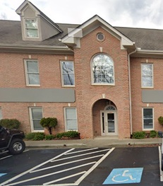 Two-story brick building with arched doorway, multiple windows, and designated handicapped parking space in front. Two-story brick building with arched doorway, multiple windows, and designated handicapped parking space in front.